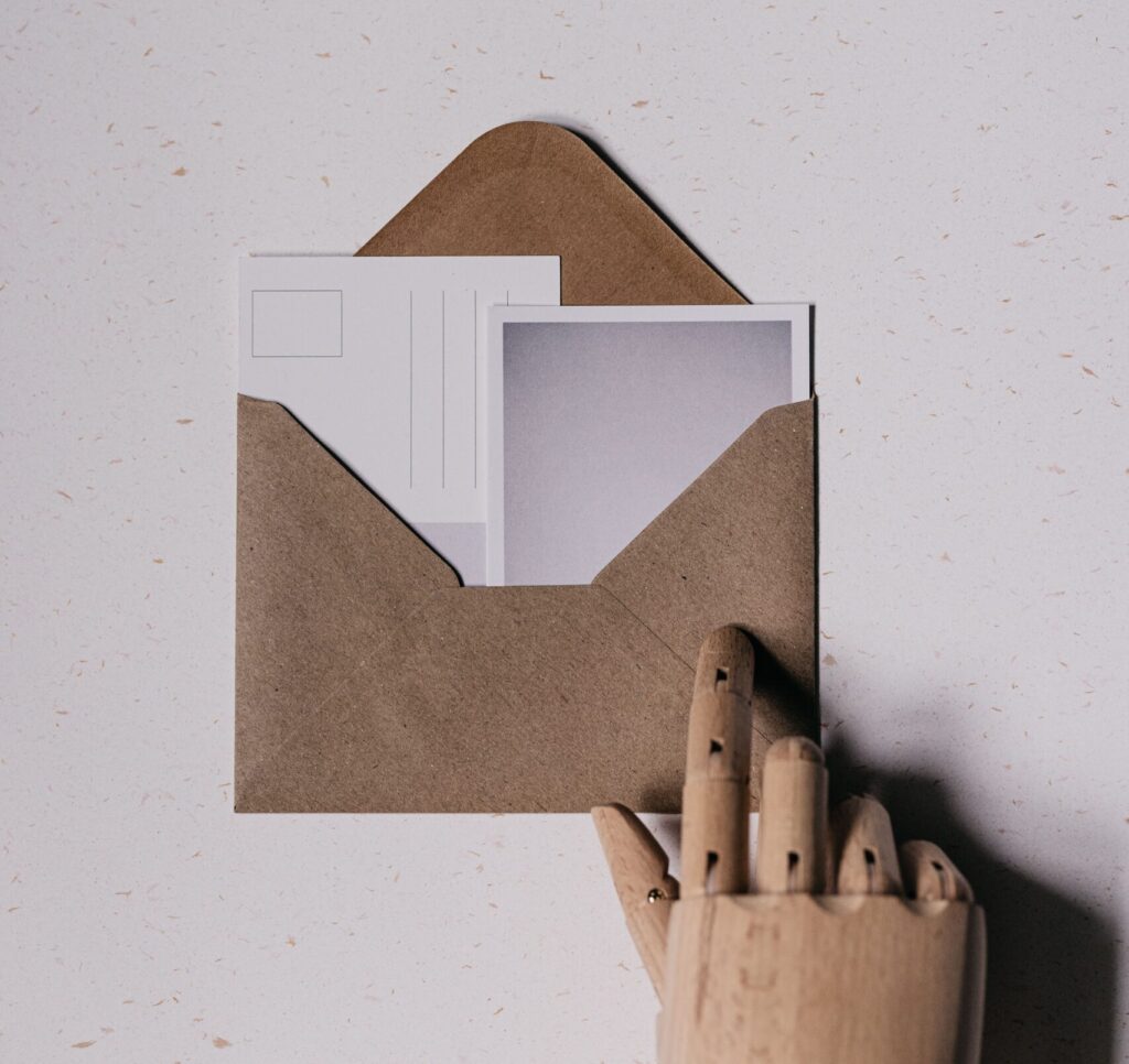 Enveloppe kraft ouverte laissant apparaître une lettre et une carte postale, symbole d'une newsletter