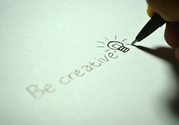 Main dessinant une ampoule à côté des mots « Be creative ».